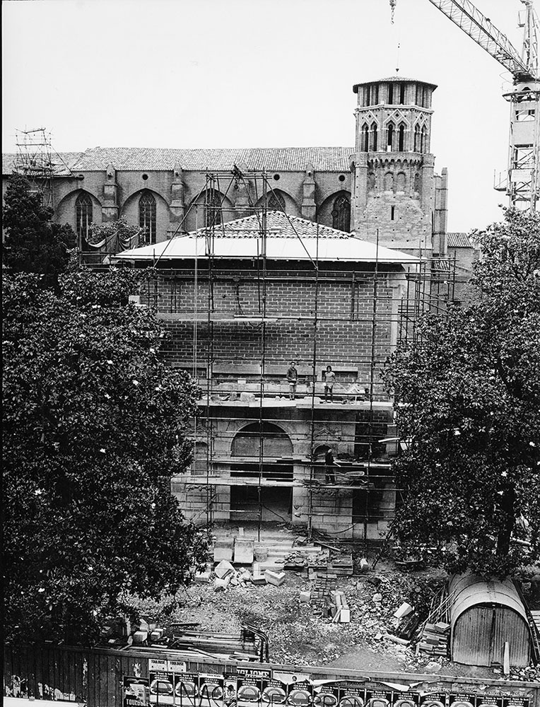 Photo en légère plongée de la construction du pavillon "Boiret" : au premier plan une zone de chantier puis des échafaudages sur la façade de l'entrée. En arrière-plan : le haut de l'église du musée et son clocher et sur la droite une grue de chantier.