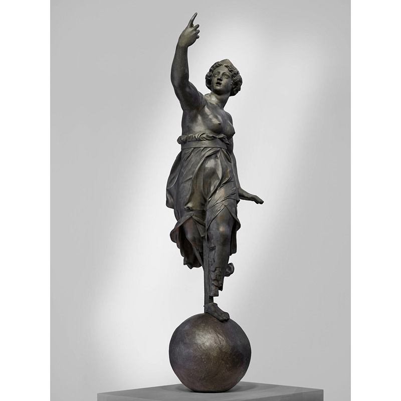 Sculpture en bronze représentant une femme en pied, reposant sur une sphère, le bras droit et l'index levés. Elle porte une tunique qui s'arrête sous la poitrine qui est dénudée. Ce personnage est Dame Tholose, allégorie de la ville de Toulouse.
