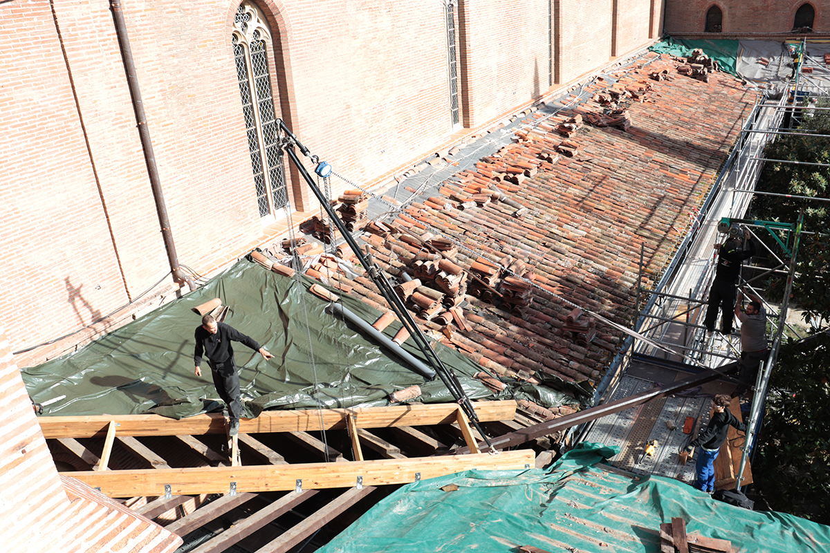 Sur le toit, une chèvre (trépied provisoire) équipée d’un palan facilite le levage des éléments de charpente