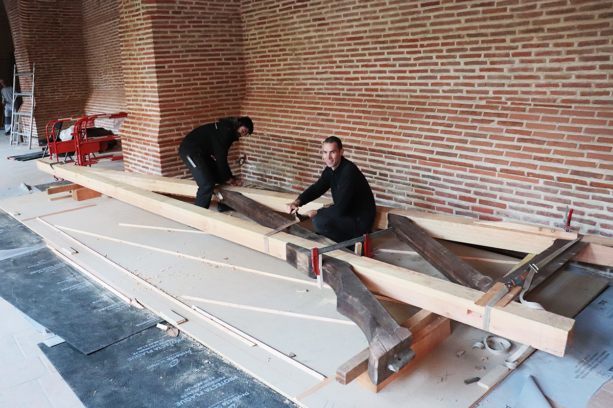 Les compagnons charpentiers réalisent un assemblage à blanc des différents éléments composant la demi-ferme