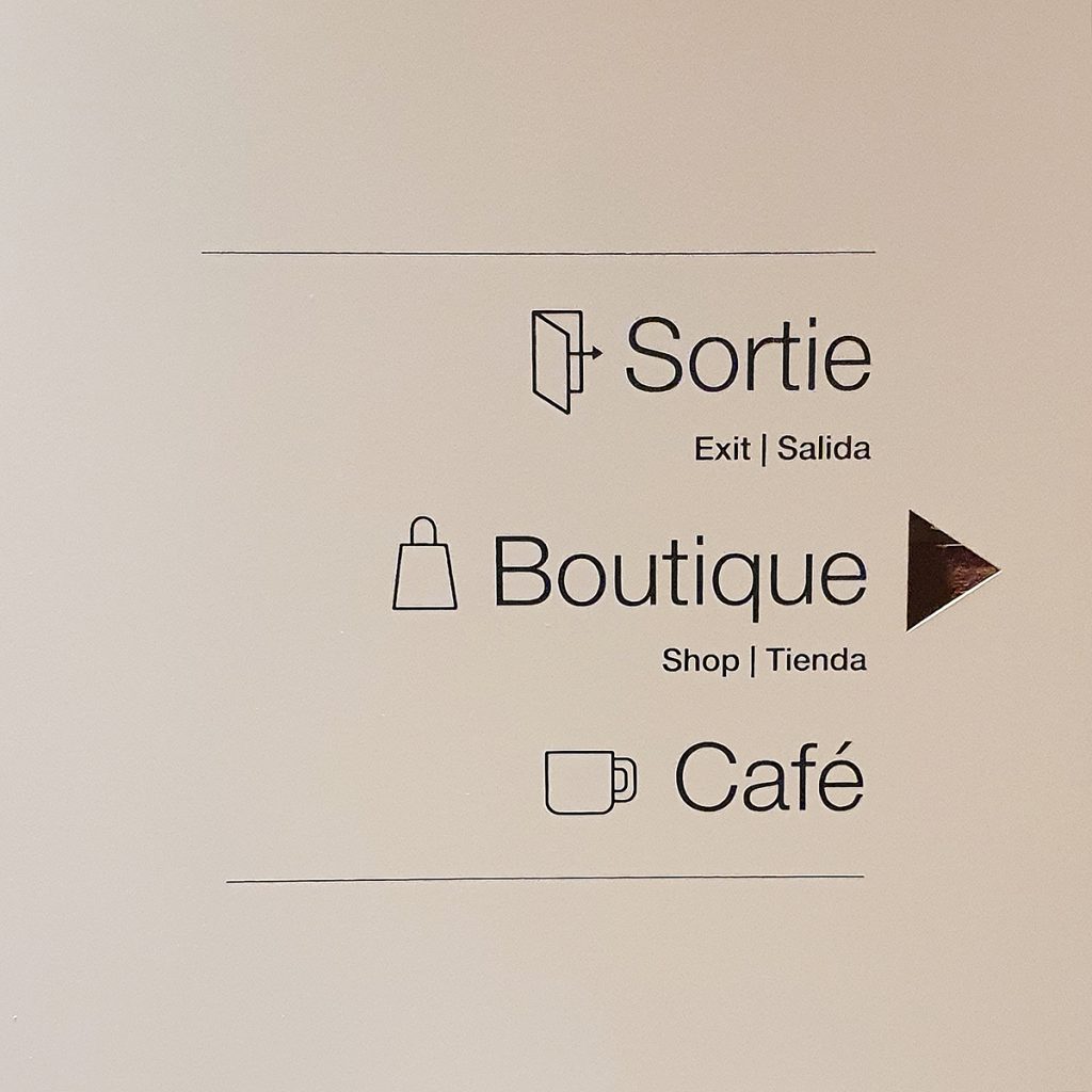 Panneau signalétique directionnel vers la boutique et le coin café du musée